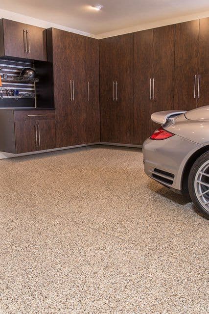 Modern garage interior with luxury sports car, organized storage cabinets, and polished floor.