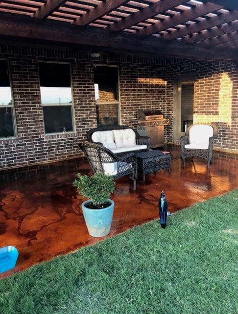 Cozy outdoor patio with wicker furniture, a grill, and a decorative plant.