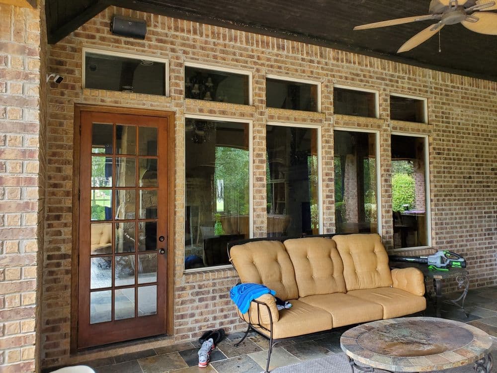 Cozy patio with brick walls, large windows, and a comfortable sofa on a stone floor.