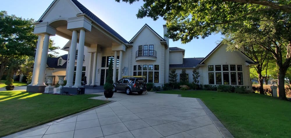 Modern luxury home with elaborate architecture and landscaped yard on a sunny day.